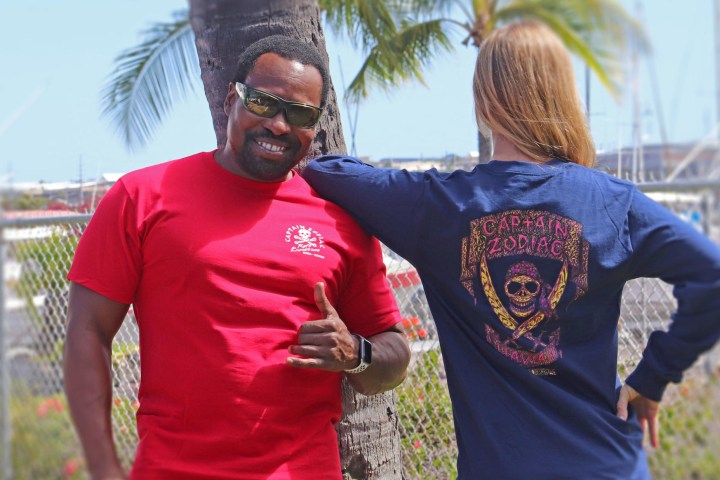 a man wearing a red shirt standing in front of a fence