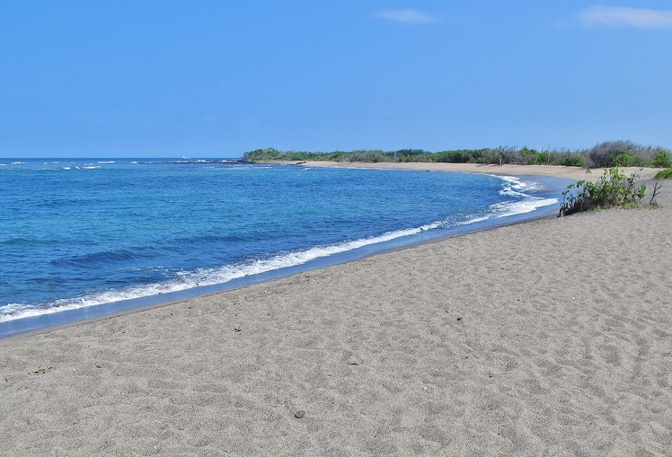 a sandy beach next to a body of water